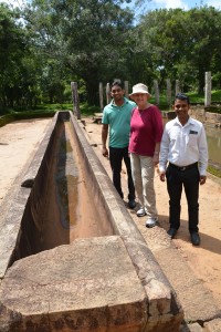 Our driver Mr. T, Julie and our local guide for the day Mr. D stand next to a xx which was used for preparing rice for the monks