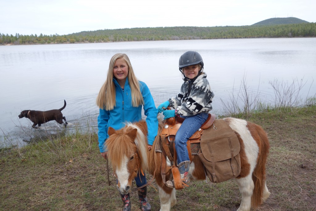 Megan and her little sister Ellie pose with the family pony Mudbud with one of the family dogs Penny splashing in the background