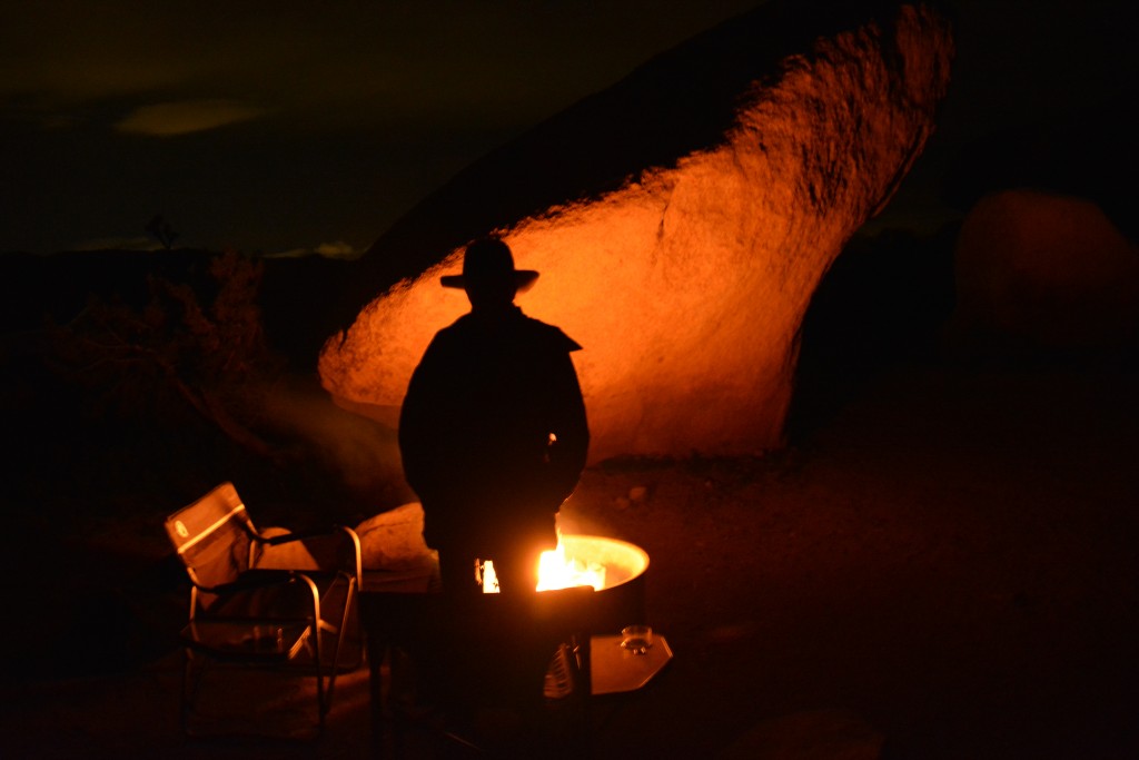 Julie silhouetted by the fire in front of a huge rock