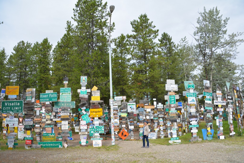 Julie standing amongst a small handful of the incredible forest of signs from all over the world